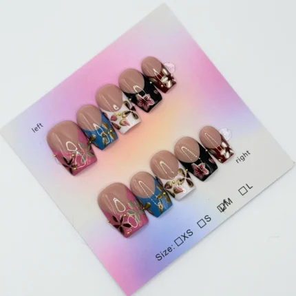 Set of short square press‑on nails with a nude base and colorful floral French tips in pink, blue, white, and black, displayed on a pastel gradient backing card.