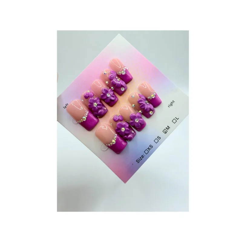 Designed with a nude base, bright purple French tips, delicate 3D purple flower clusters, and sparkling rhinestone accents, this set blends classic style with modern detail.