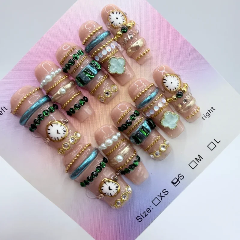 Handmade 3cm coffin press-on nails featuring gold bangle-style 3D art, pearls, watch face charms, and a mint green clover centerpiece on a nude base.