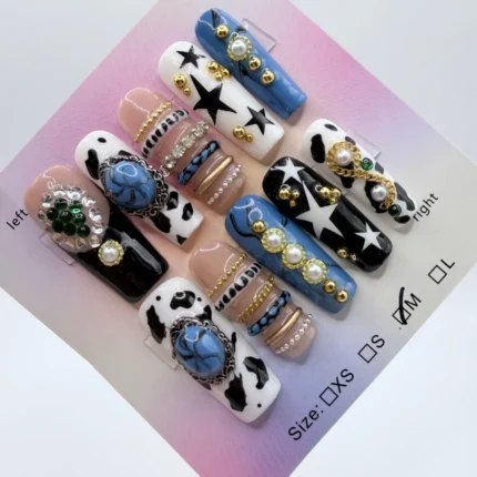 Handmade 3cm square press-on nails featuring blue denim texture, black cow print, and 3D gold bangle charms with blue stones and pearls.