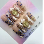 Handmade square press-on nails with royal blue rhinestones, 3D white carved flowers, and gold religious cross charms on a nude base.