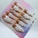 Handmade stiletto press-on nails 3cm length featuring 3D white sculpted flowers and silver rhinestones on a nude gel base.