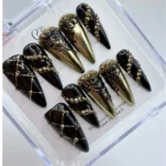 Luxury baroque gothic press on nails featuring matte black textures and intricate handpainted gold trim.