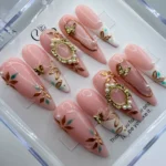 Luxury pink press on nails featuring an elegant rose base coat with intricate 3D regal gold filigree patterns.