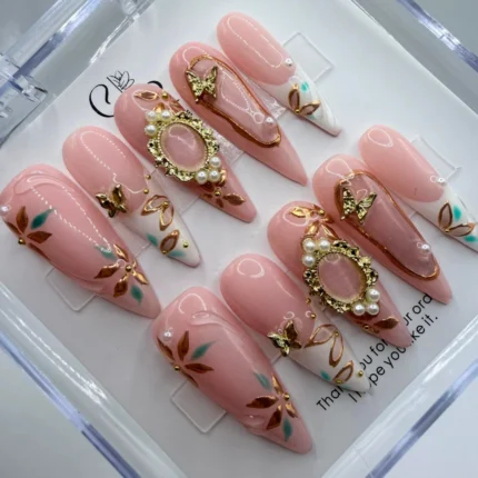 Luxury pink press on nails featuring an elegant rose base coat with intricate 3D regal gold filigree patterns.